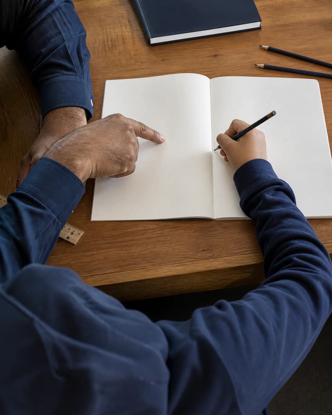 A parent guiding a child's hand as the child writes in a notebook
