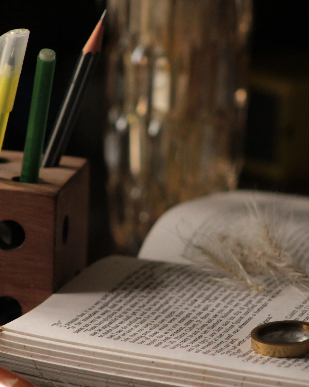 An open book with coloured pencils and a magnifying glass on a study desk