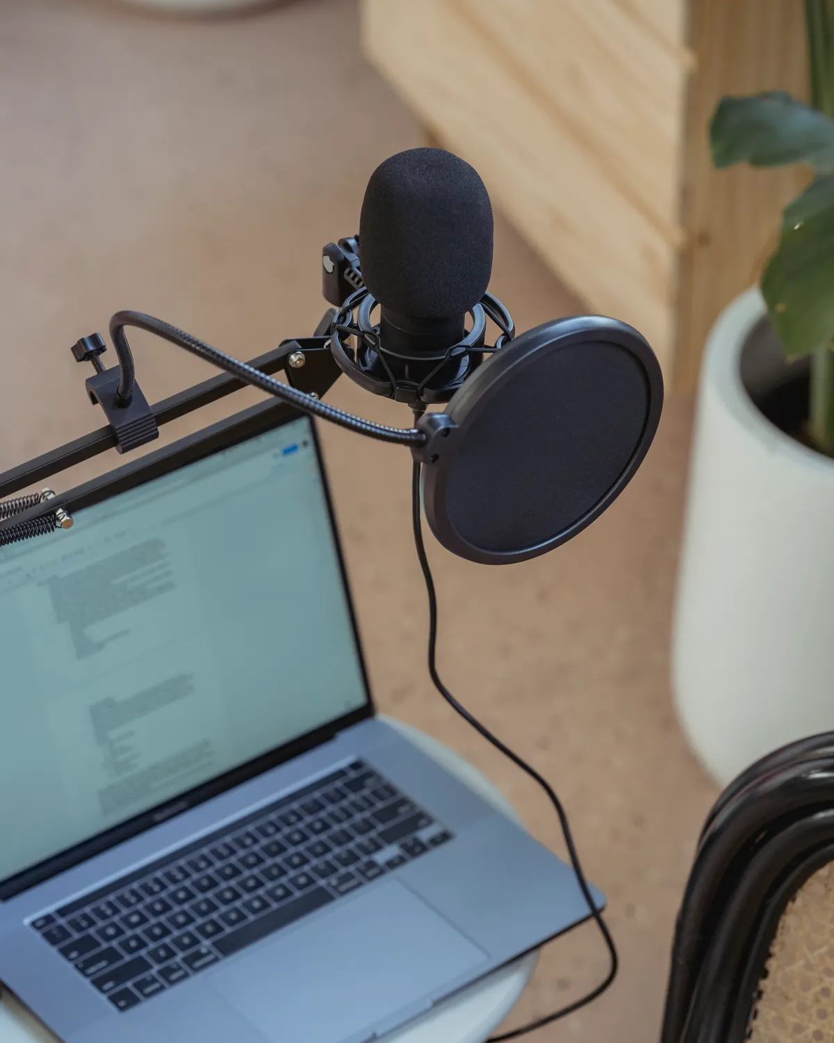 A podcast microphone and laptop in a warm home studio